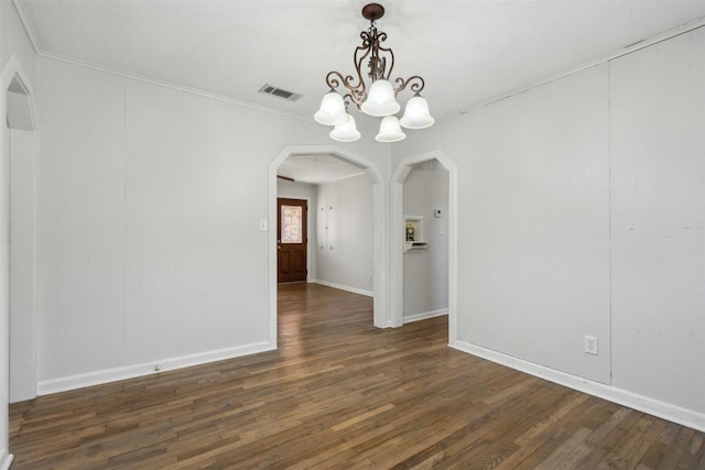 spare room featuring arched walkways, a notable chandelier, wood finished floors, visible vents, and ornamental molding