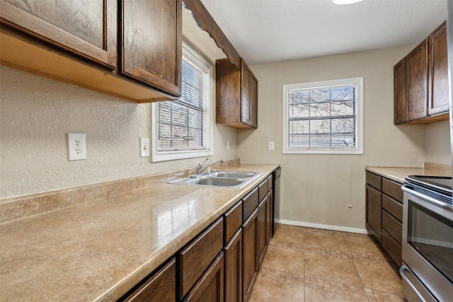 kitchen with light countertops, plenty of natural light, a sink, and stainless steel range with electric cooktop