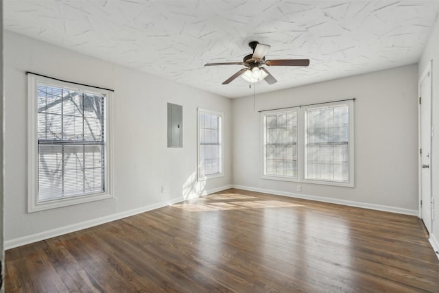 unfurnished room featuring a ceiling fan, electric panel, baseboards, and wood finished floors