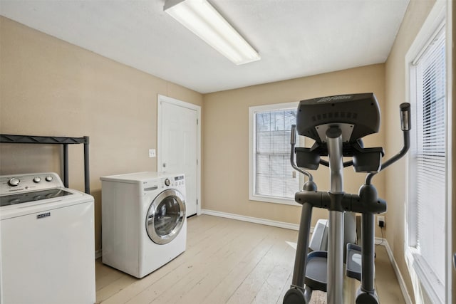 laundry room featuring light wood-style floors, laundry area, baseboards, and washing machine and clothes dryer