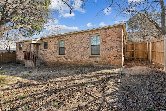 back of property with crawl space, a fenced backyard, and brick siding