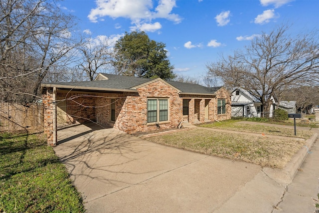 view of front of house featuring driveway, a shingled roof, a front lawn, and brick siding