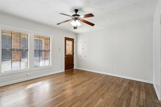 empty room with a ceiling fan, baseboards, and wood finished floors