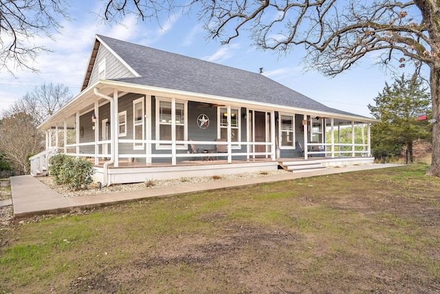 back of house with covered porch, a yard, and a shingled roof