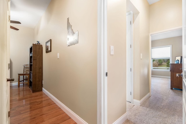 hall with baseboards and light colored carpet