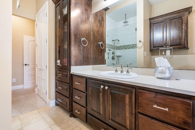 bathroom featuring a tile shower, vanity, baseboards, and tile patterned floors