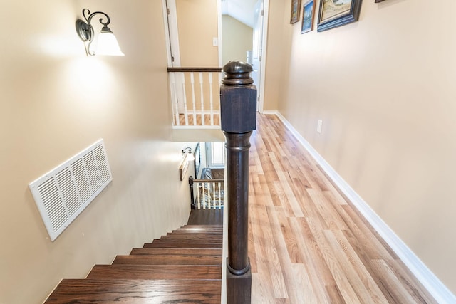 stairs with visible vents, baseboards, and wood finished floors