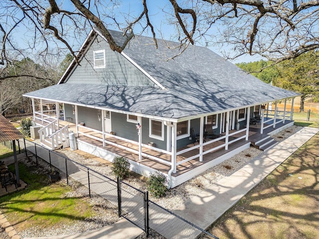 farmhouse with covered porch, a shingled roof, fence private yard, and a gate