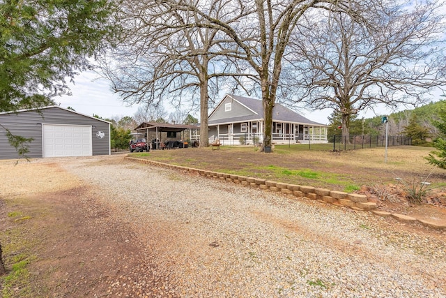 view of front facade with driveway, a detached garage, fence, an outdoor structure, and a front yard