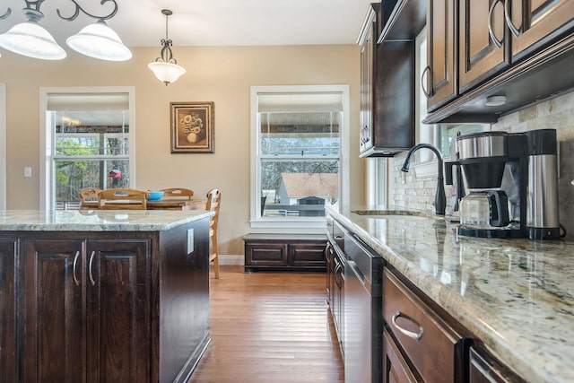 kitchen featuring dark wood-style flooring, a sink, dark brown cabinets, tasteful backsplash, and pendant lighting