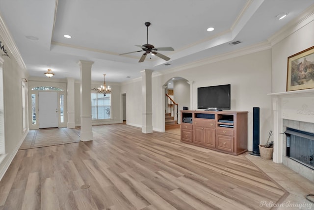 unfurnished living room featuring ornate columns, a tray ceiling, a fireplace, and visible vents