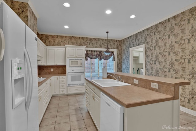 kitchen featuring white appliances, a sink, white cabinets, an island with sink, and wallpapered walls