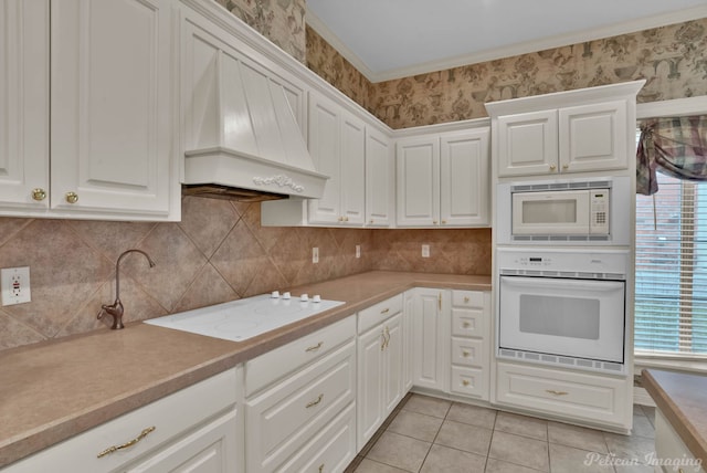kitchen featuring light countertops, white cabinets, custom exhaust hood, white appliances, and light tile patterned flooring