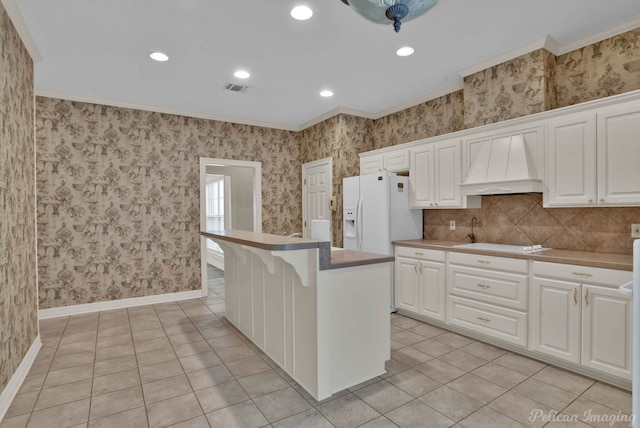 kitchen with white appliances, white cabinetry, baseboards, wallpapered walls, and custom range hood