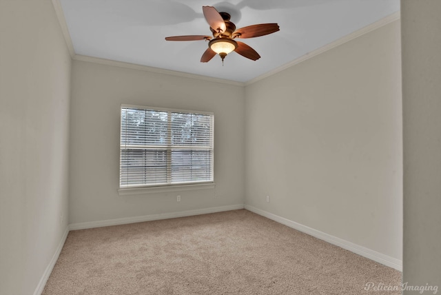 carpeted spare room featuring a ceiling fan, baseboards, and crown molding