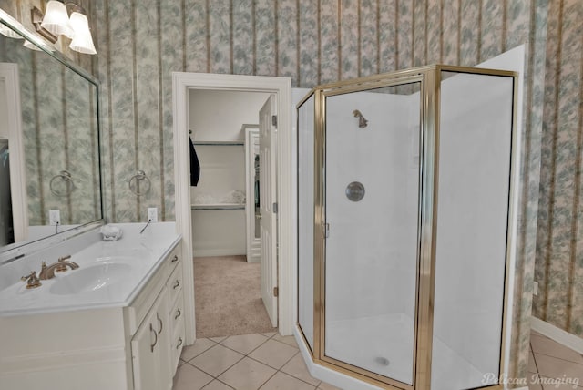 bathroom featuring wallpapered walls, tile patterned flooring, a spacious closet, vanity, and a shower stall