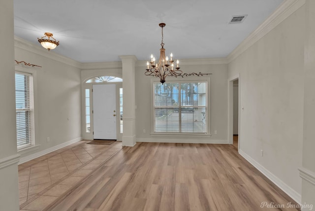 foyer with an inviting chandelier, a wealth of natural light, light wood finished floors, and visible vents
