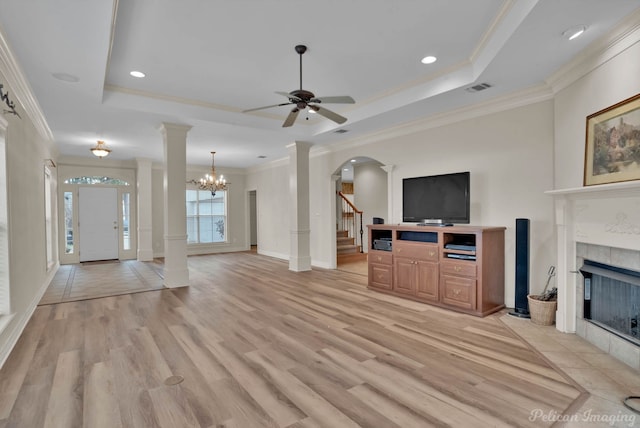 living room featuring decorative columns, visible vents, a raised ceiling, and a tiled fireplace