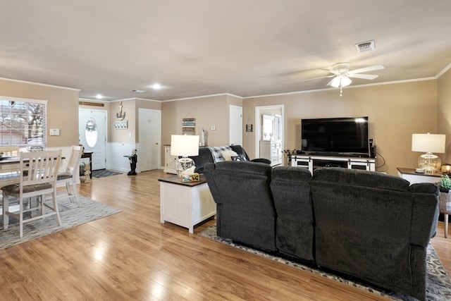 living area with ceiling fan, visible vents, baseboards, light wood-style floors, and crown molding