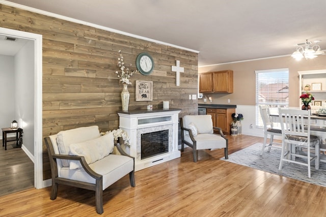 living area with light wood finished floors, visible vents, a premium fireplace, crown molding, and a notable chandelier