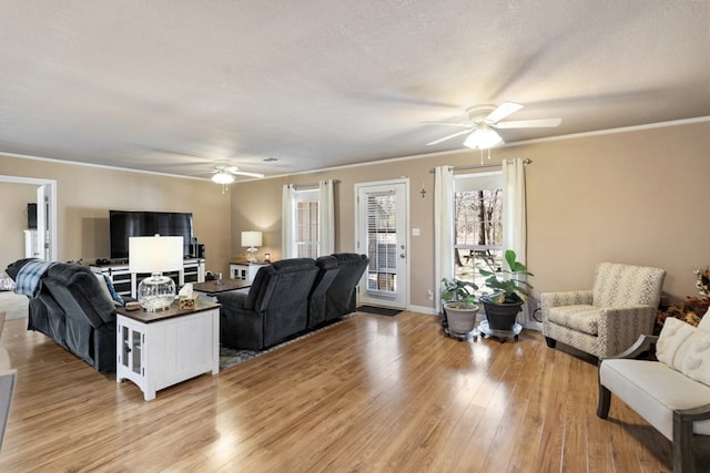 living area with crown molding, baseboards, a ceiling fan, and light wood-style floors