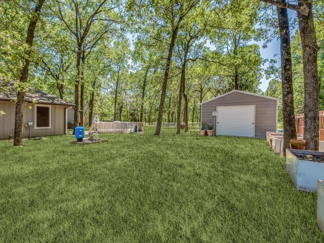 view of yard with a garage, driveway, an outbuilding, and fence