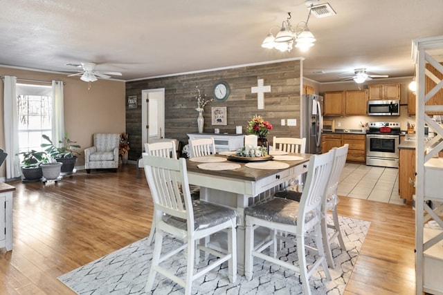 dining space featuring a ceiling fan, light wood-type flooring, visible vents, and ornamental molding