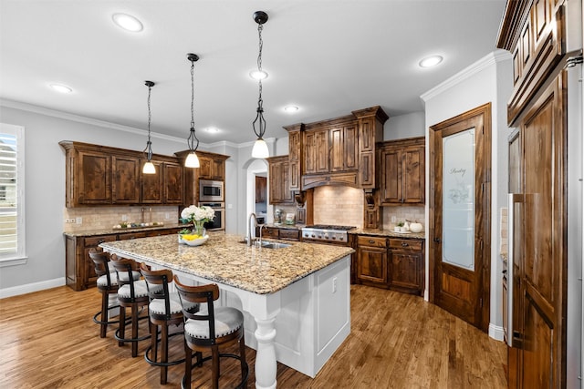 kitchen featuring appliances with stainless steel finishes, arched walkways, crown molding, and a sink