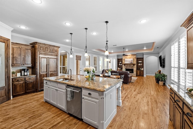 kitchen with arched walkways, a fireplace, a sink, and dishwasher