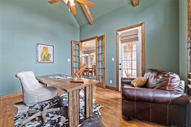 office area featuring ceiling fan with notable chandelier, visible vents, baseboards, light wood-type flooring, and beam ceiling