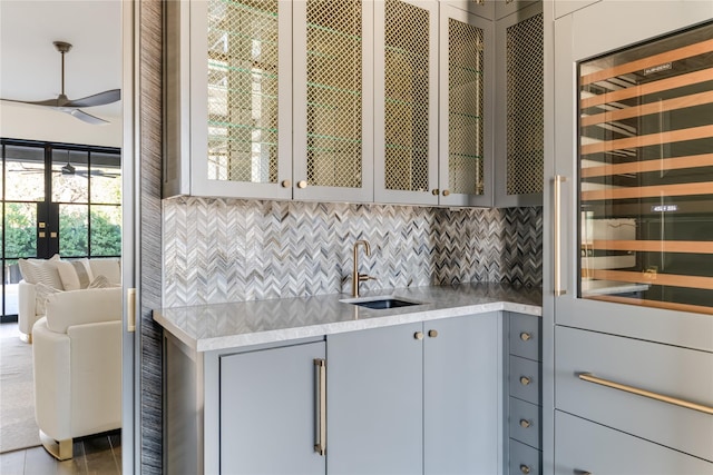 kitchen featuring a ceiling fan, gray cabinets, light countertops, and a sink