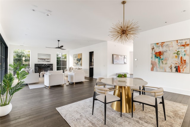 dining area with a ceiling fan, dark wood finished floors, a fireplace, and baseboards