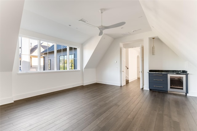 additional living space featuring dark wood-type flooring, lofted ceiling, baseboards, and a ceiling fan