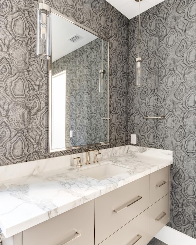 bathroom with vanity, visible vents, and wallpapered walls