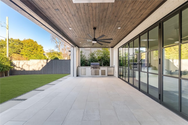 view of patio with a fenced backyard, ceiling fan, grilling area, and an outdoor kitchen