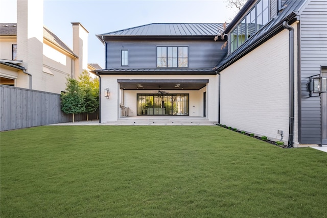 rear view of property with a standing seam roof, brick siding, fence, and a lawn