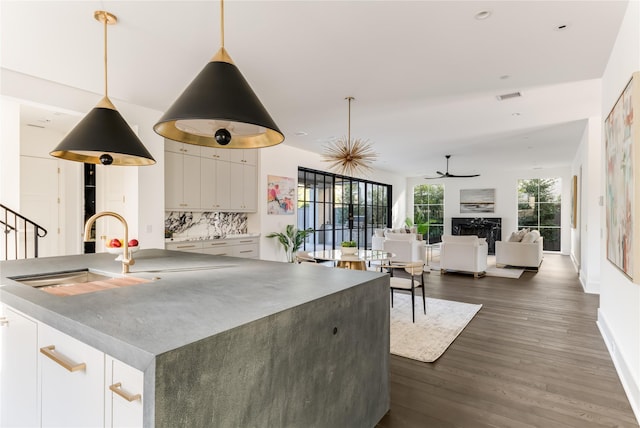 kitchen featuring a fireplace, a sink, dark wood finished floors, and white cabinetry