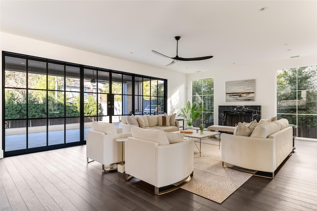 living room featuring dark wood-style floors, a high end fireplace, and ceiling fan