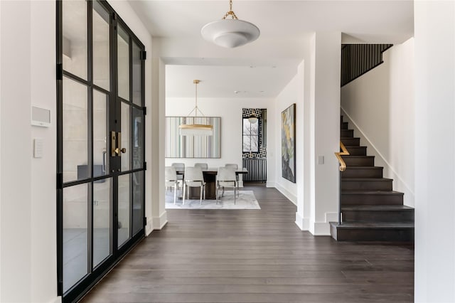 entryway with dark wood-style flooring, baseboards, and stairs