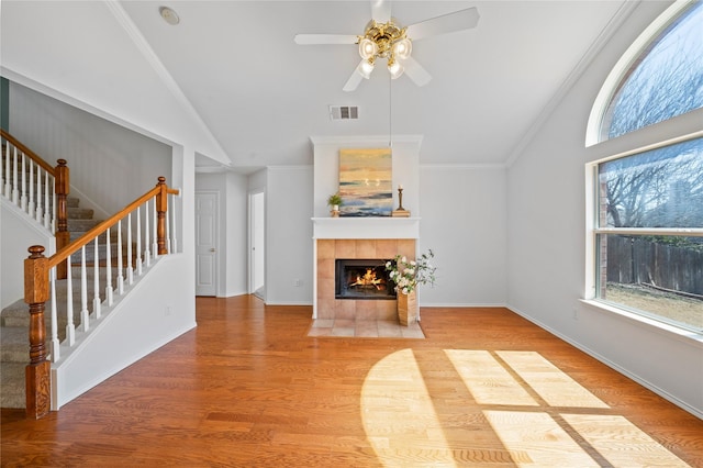 unfurnished living room with stairs, vaulted ceiling, a fireplace, visible vents, and a ceiling fan