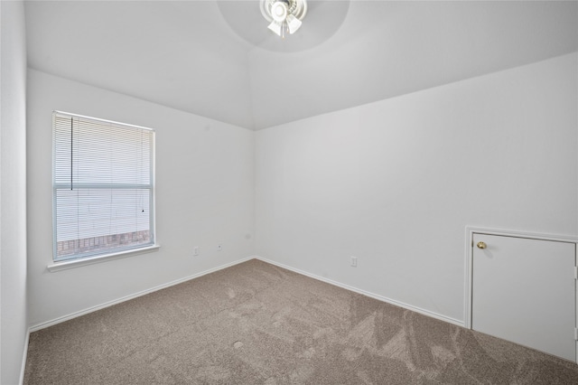 empty room with ceiling fan, vaulted ceiling, carpet, and baseboards