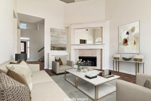 living room featuring baseboards, a fireplace, stairway, wood finished floors, and a towering ceiling