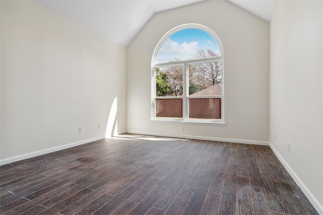 unfurnished room featuring vaulted ceiling, dark wood finished floors, and baseboards