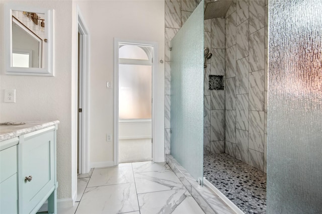 full bathroom featuring marble finish floor, vanity, and a walk in shower