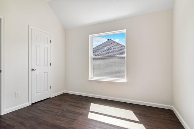 unfurnished room with dark wood-style floors, vaulted ceiling, and baseboards