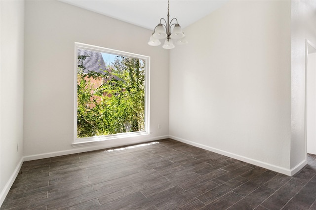 unfurnished room with a wealth of natural light, dark wood-style flooring, baseboards, and an inviting chandelier