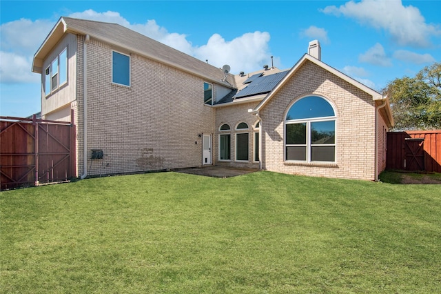 back of house featuring a gate, brick siding, a yard, and a fenced backyard