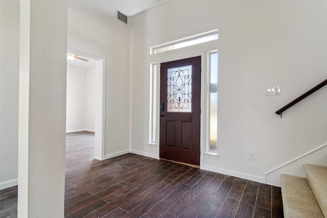 foyer entrance featuring visible vents, dark wood finished floors, baseboards, and stairs