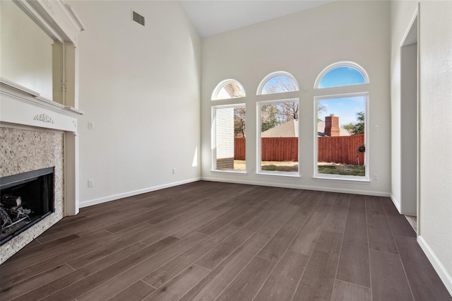 6114 Baskerville Dr, Rowlett, TX 75087 - unfurnished living room with a high ceiling, dark wood finished floors, healthy amount of natural light, a tiled fireplace, and baseboards