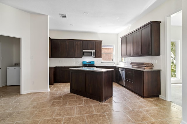 kitchen featuring stainless steel appliances, washer / clothes dryer, visible vents, and dark brown cabinets